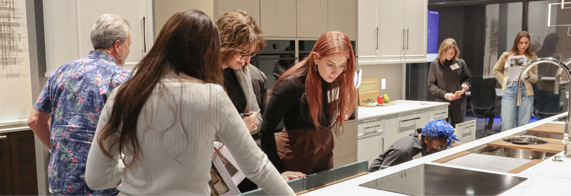 Image (Designers and dealers gathered around a Signature island, opening drawers and reviewing finishes)